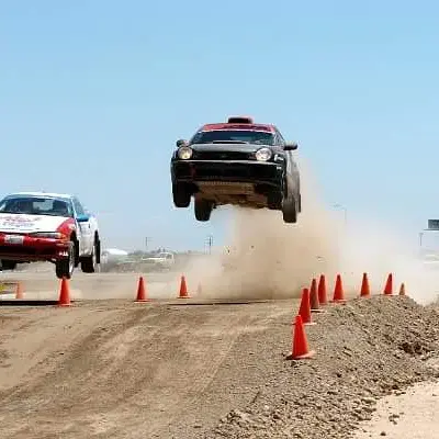 A car jumps over a dirt track during a rally race.